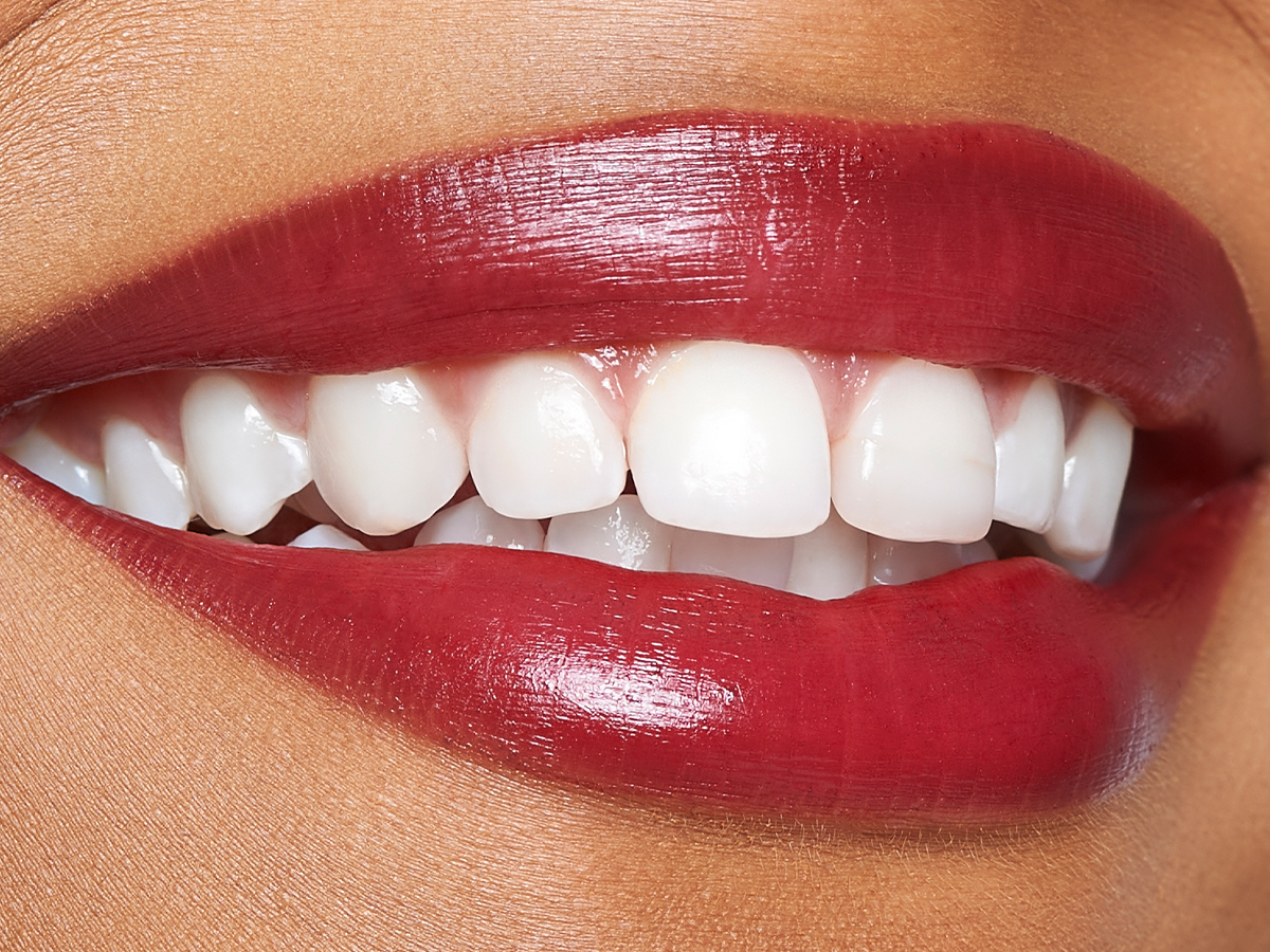Lips close-up of a medium-tone model wearing a vibrant, cherry-red lip tint.
