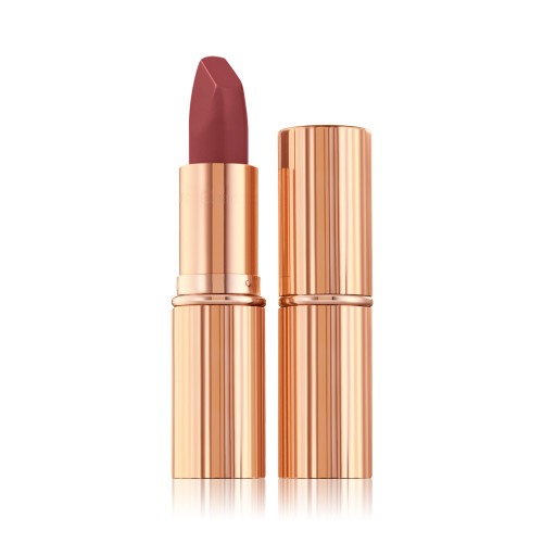 an open matte lipstick in a warm, berry-pink shade in a standard-sized, metallic, golden tube next to an unopened lipstick encased in a metallic, golden tube. 