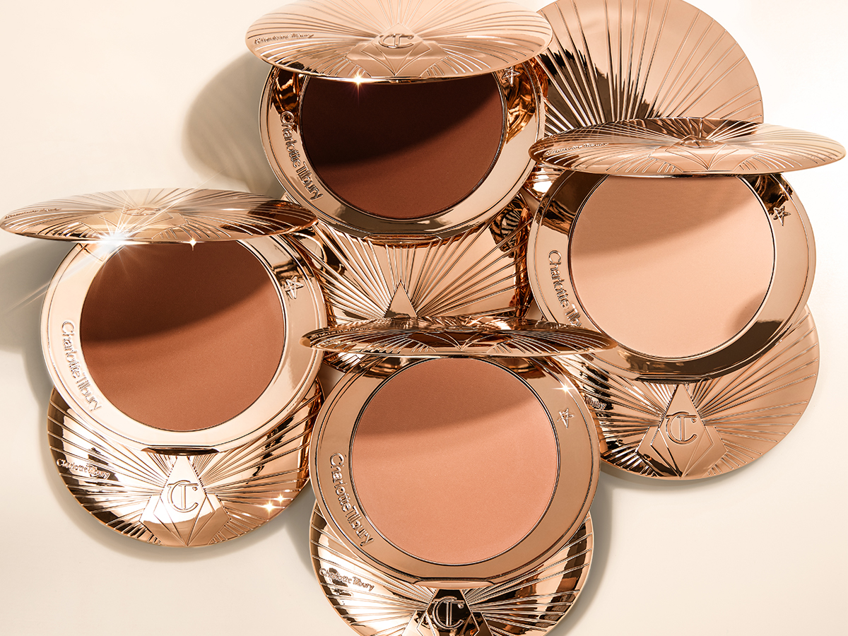 Una collezione di confezioni chiuse del bronzer, con tre prodotti aperti dai toni chiari, medi e medio-scuri.