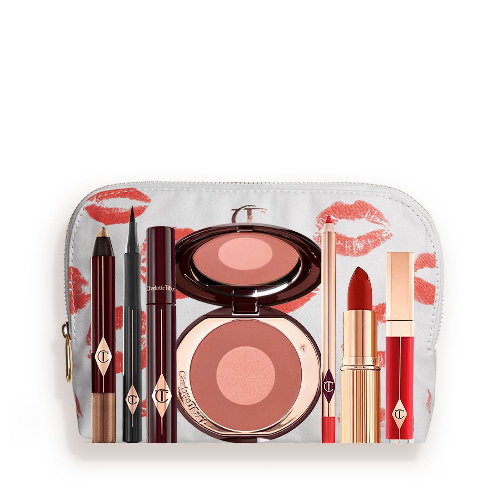 A white-coloured makeup pouch with an open two-tone blush in cool-toned terracotta and warm pink with a mascara, eyeliner pen, an open lipstick in bold red, lip liner pencil in blood-red, and a lip gloss in bright red. 