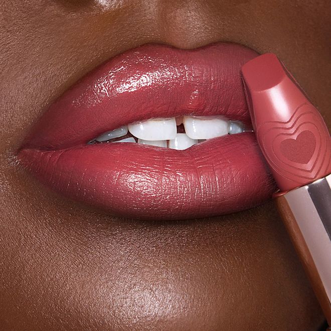 K.I.S.S.I.N.G in Rosy Seduction deep-tone lips close-up Lips close-up of a deep-tone model applying a rosy pink lipstick with a satin finish.