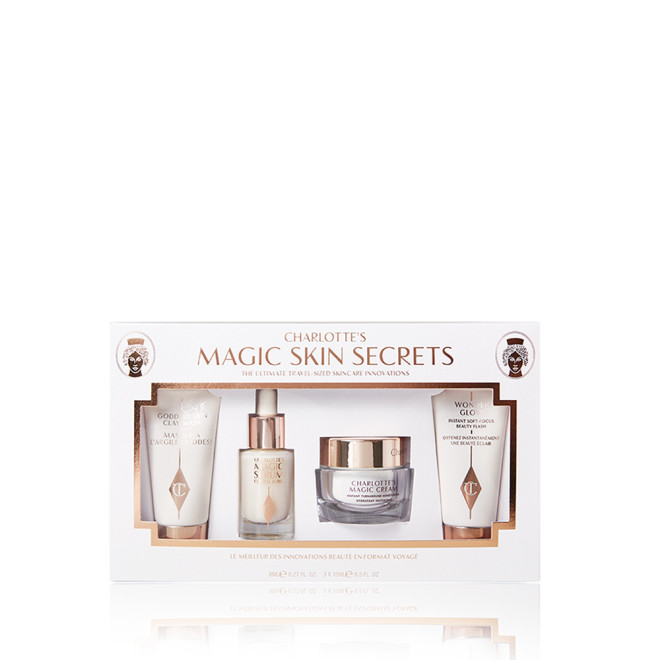 Pearly-white face cream in a glass jar with gold-coloured lid, luminous face serum in a glass bottle with a white and gold-coloured dropper lid, and a clay mask and glowy primer in white-coloured bottles with gold-coloured lids, all packed in a white-coloured box. 