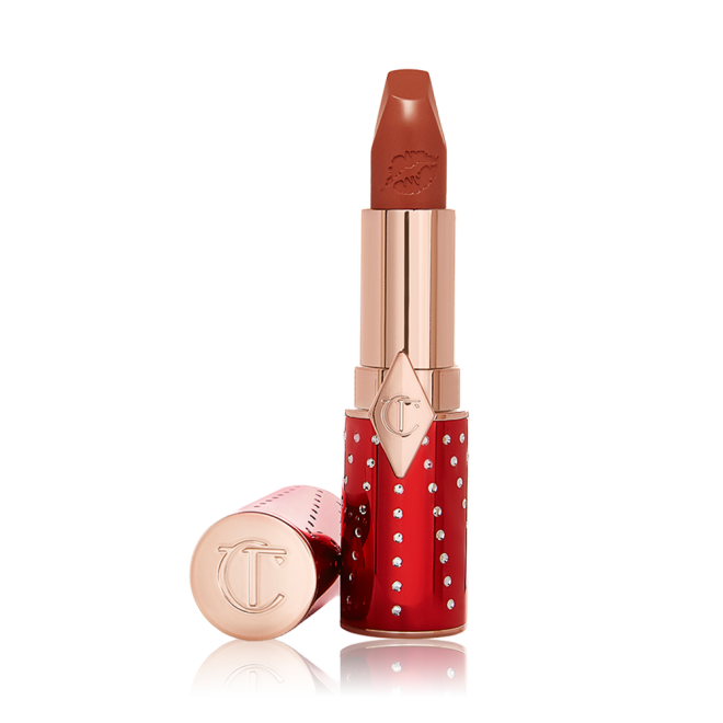 An open tube of lipstick in sparkly red and gold packaging in a matte brick red shade,