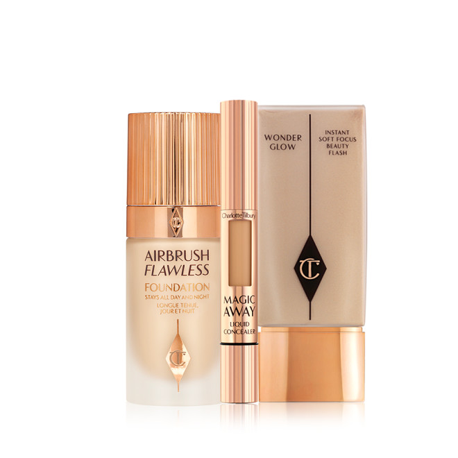 Creamy liquid concealer in a sleek gold-coloured tube with a soft sponge end for application, foundation in a frosted glass bottle with a gold-coloured lid, and foundation in a rectangular bottle with a gold-coloured lid.