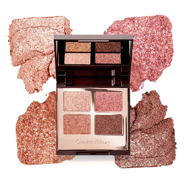 An open, mirrored-lid quad eyeshadow palette with shimmery nude pink, copper, brown, and fawn eyeshadows with its swatches behind it. 