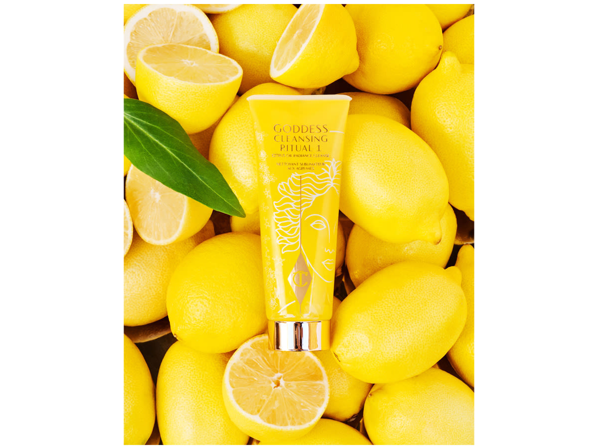 A citrus-based cleanser in bright yellow and white-gold-coloured packaging placed on a bed of lemons. 