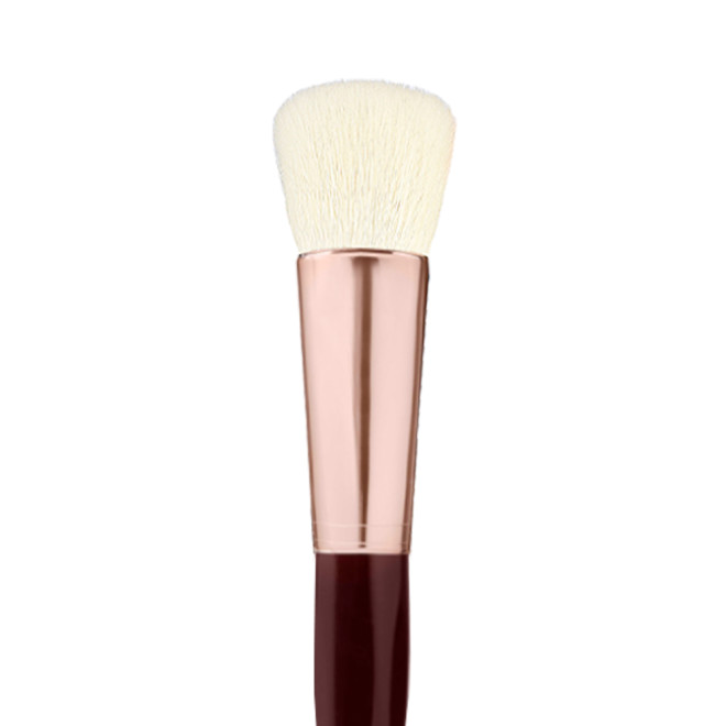 A face blending brush with cream-coloured bristles with a rose-gold and dark crimson handle. 