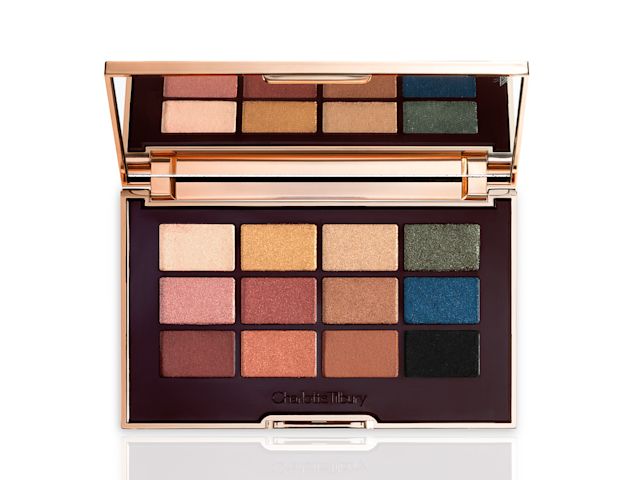 An open, mirrored-lid eyeshadow palette with nude brown, green, blue, black, gold, and pink shades.