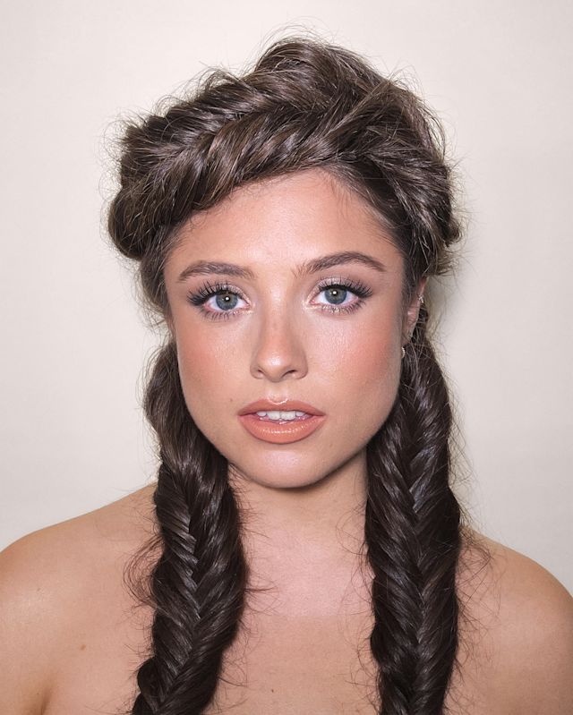 Close-up of a fair-tone model with blue eyes wearing soft peach matte lipstick with brownish-peach blush, and brown and beige eye makeup.