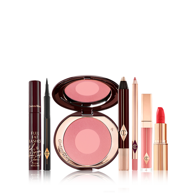 A 7-piece makeup kit containing a mascara, a black eyeliner pen, a pink two-tone blush, cream eyeshadow stick, nude pink lip liner pencil, nude pink lip gloss, and a bright orange-red lipstick. 