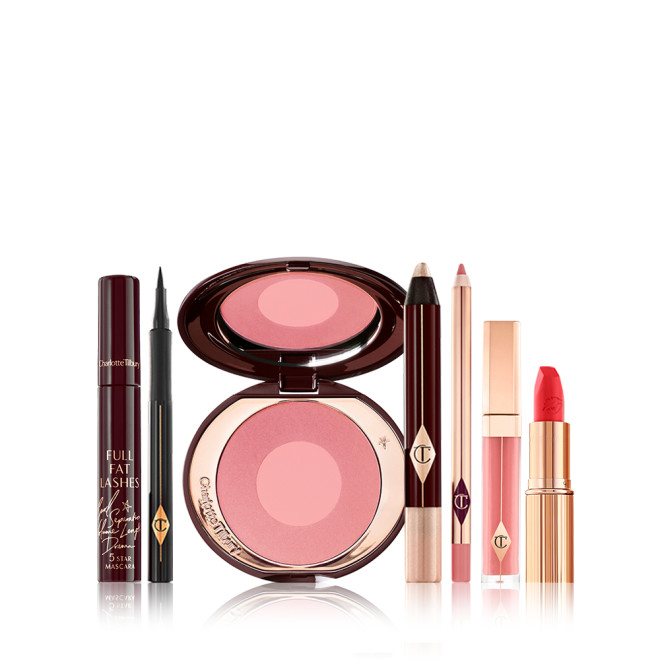 A 7-piece makeup kit containing a mascara, a black eyeliner pen, a pink two-tone blush, cream eyeshadow stick, nude pink lip liner pencil, nude pink lip gloss, and a bright orange-red lipstick. 