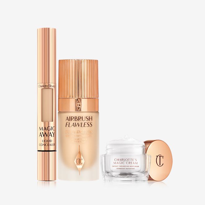 charlottes-magic-airbrush-complexion-kit-NA-packshot Creamy liquid concealer in a gold-coloured tube with a gold-coloured lid, foundation in a frosted glass bottle with a gold-coloured lid, and pearly-white face cream in a glass jar with a gold-coloured lid.