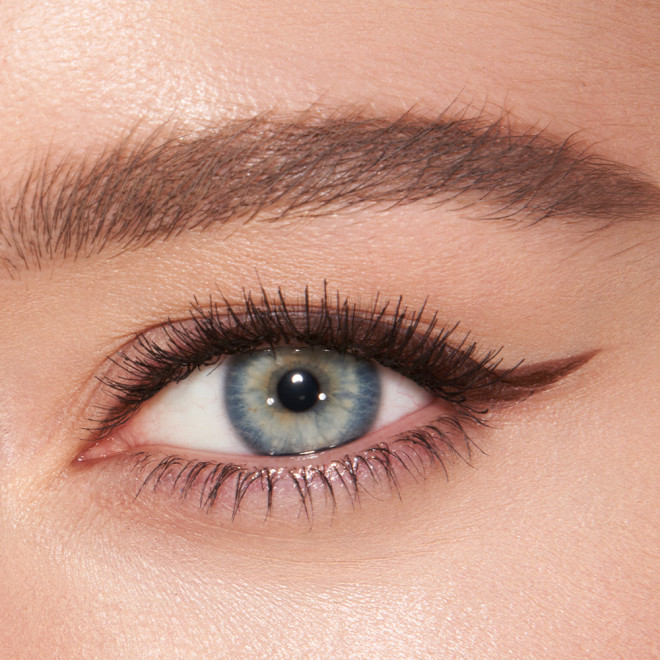 Eye close-up of a fair skin model with blue eyes wearing a chocolate-brown eyeliner in a soft wing. 