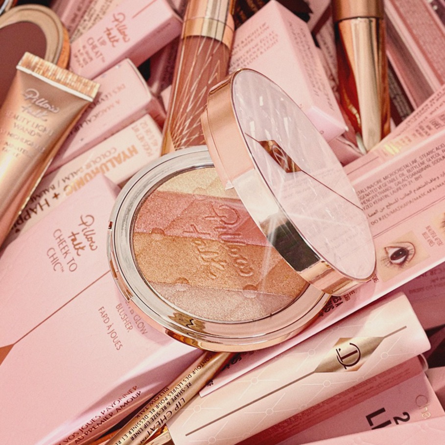 An open, multi-colour highlighter compact with champagne, rose gold, coppery-bronze, and oyster grey shades in rose gold-coloured packaging.