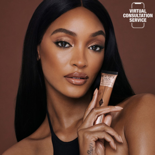 Deep-tone model wearing shimmery brown eye makeup with nude pink lip gloss, and luminous, skin-like foundation.