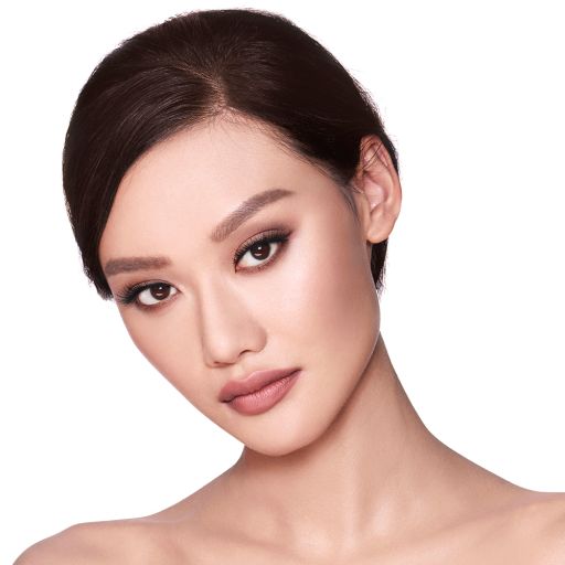 A fair-tone model with brown eyes wearing smokey brown eye makeup with muted pink blush and glossy terracotta-brown lips