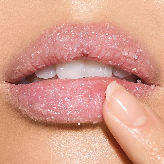 Charlotte's Magic Lip Scrub on light-tone lips close-up Lips close-up of a light-tone model with a thick layer of white-coloured lip scrub with sugar crystals on her lips.