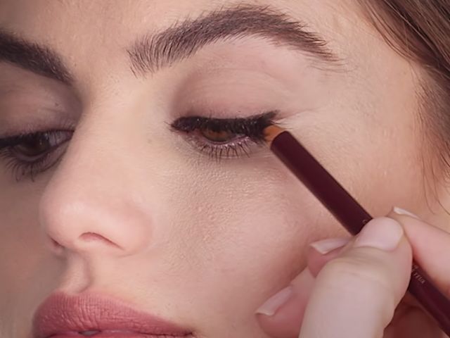 Close-up of a light-tone model getting dark brown kohl liner applied. 