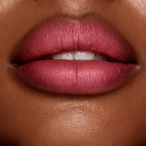Lips close-up of a deep-tone model wearing a matte, berry-rose lipstick. 