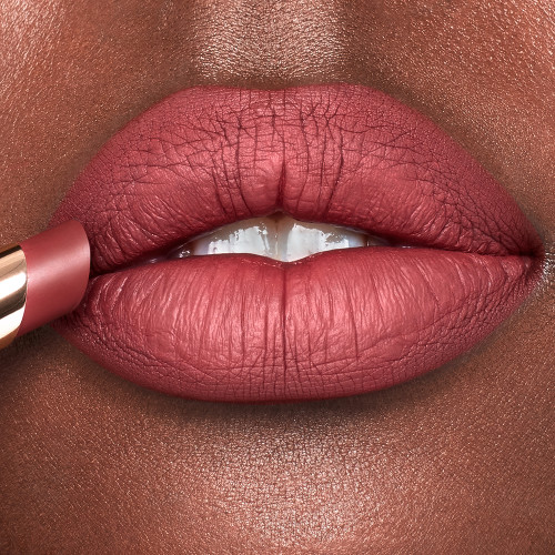 Lips close-up of a deep-tone model wearing dusty rose lipstick with a matte finish.