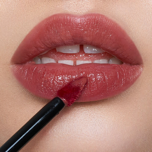Lips close-up of a light-tone model applying a soft pink lip tint.