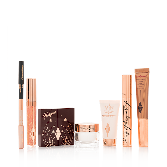 Charlotte's Hollywood Makeup Look displayed A double-ended eyeliner pencil in black and nude beige colours, high-shine lip gloss in a peachy-rose colour, quad eyeshadow palette with a brown-coloured lid, glowy, pearly-white face cream, liquid highlighter wand in rose gold, black mascara in a gold-coloured tube, and luminous primer.