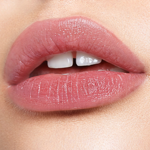 Lips close-up of a fair-tone model wearing a sheer, soft tea-rose-coloured lip tint. 