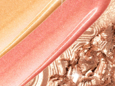 Swatches of liquid highlighters in warm golden and rose pink and a powder highlighter in coppery-champagne. 