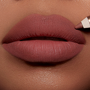Lips close-up of a deep-tone model applying a rich velvety nude pink lip liner pencil.