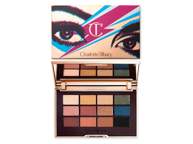 An open, mirrored-lid eyeshadow palette with nude brown, green, blue, black, gold, and pink shades along with golden-coloured packaging with a lightning bolt in dark pink and blue colour along with an illustration of eyes in dark pink and black colour. 