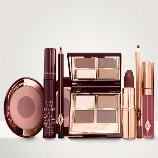 A quad eyeshadow palette in shades of champagne, gold, and bronze, a dark brown eyeliner pencil, mascara, a two-tone brown and pink powder blush, tawny-brown lip liner, a maroon lipstick, and a warm pinkish-red lip gloss. 