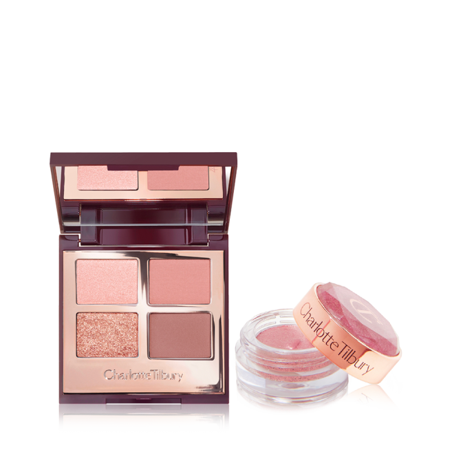 An open, mirrored-lid quad eyeshadow palette in pink and gold shades with a shimmery, cream eyeshadow in a nude-pink shade in a glass pot with its lid removed.