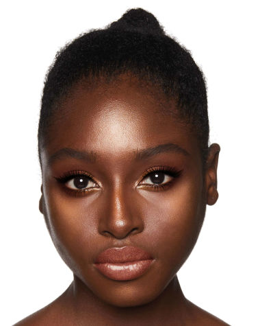 A deep-tone model with brown eyes wearing shimmery copper and gold eye makeup with black eyeliner, glowy bronzed cheeks, and pinkish-brown lipstick with gloss on top. 