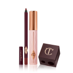 A berry-brown eyeliner pencil, black mascara with nude pink bottle and gold-coloured lid, and a dark crimson-coloured pencil and eyeliner sharpener.

