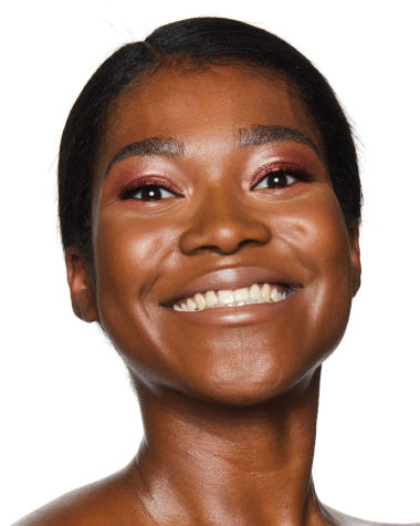 Deep-tone model with brown eyes wearing a dusky rose-pink cream eyeshadow with nude peach matte lipstick. 