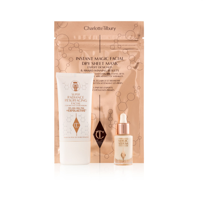 An exfoliating, wash-off mask in a white-coloured tube with a travel-size bottle of luminous face serum with a dropper lid, and a face mask in rose-gold-coloured foil packaging.