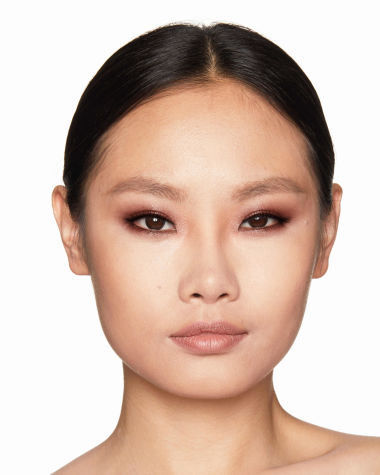 Fair-tone model with brown eyes wearing shimmery topaz and brown eye shadow with nude peach lipstick. 