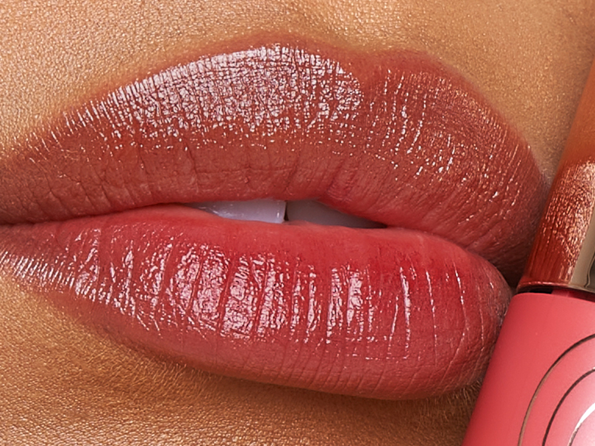 Lips close-up of a medium-tone model wearing a soft, peachy-brown lip tint.