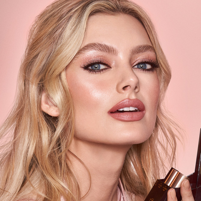 Fair-tone model with blue eyes wearing shimmery pink eyeshadow with nude pink blush and lip stain, and dewy opal-coloured highlighter for a fresh, date-night makeup look.