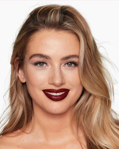 Fair-tone model with grey eyes wearing a moisturising lipstick balm in a berry shade with a high-shine finish.