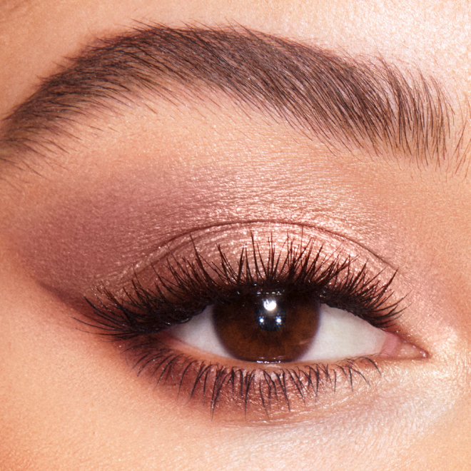 Eye close-up of a medium skin model with brown eyes wearing shimmery rose gold and champagne eyeshadow. 