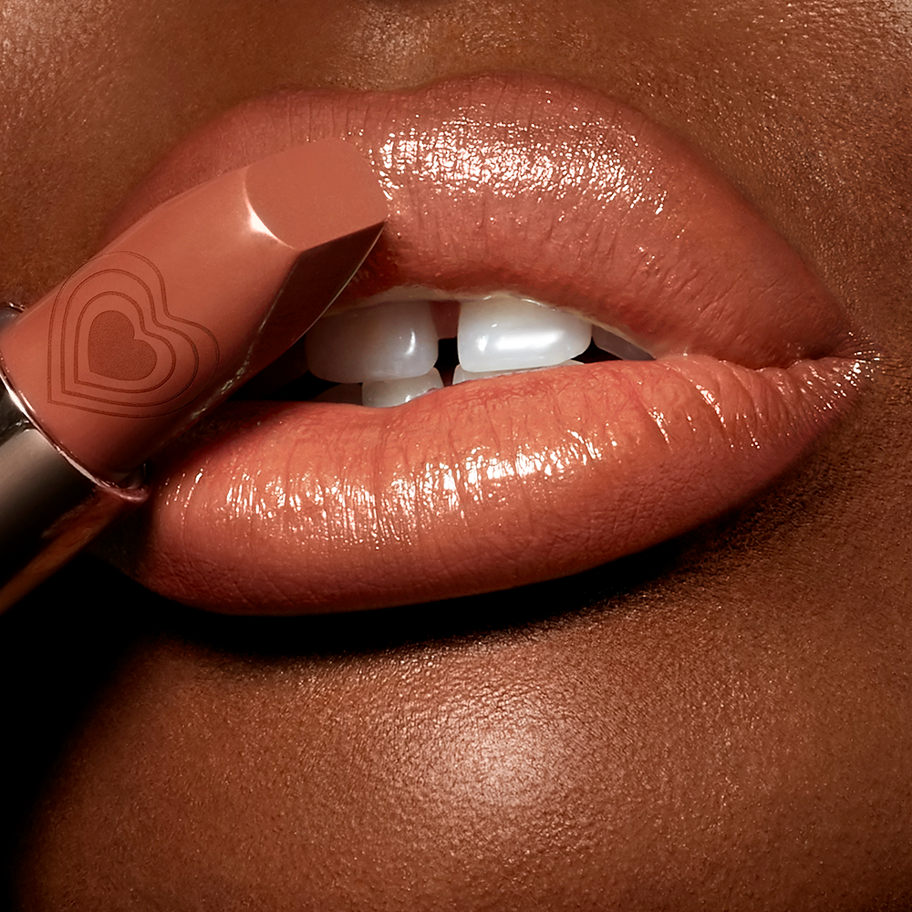 Lips close-up of a deep-tone model wearing a universally flattering, peachy-nude lipstick with a satin-finish.