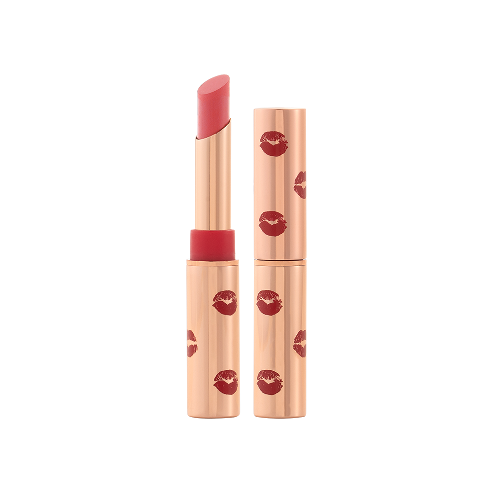 Two identical lipsticks, with and without lid, in a neutral rosy-pink colour with a matte finish, in gold-coloured tubes with red-coloured kiss print all over the tube.