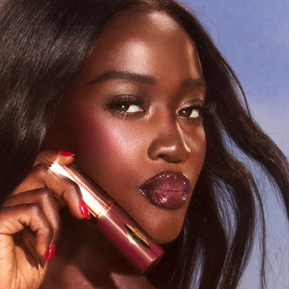 Deep model wearing and holding berry shade blush. 