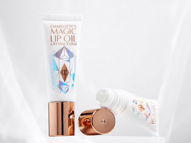 Two lips oil, with and without lid, in white tubes with reflective, geometric patterns on them, and rose-gold-coloured lids. 