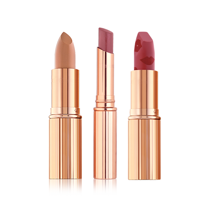 Three open lipsticks, one a satin finish nude sandy brown, glossy lipstick in a berry-pink shade, and matte lipstick in a nude berry-pink shade, with all three in gold-coloured tubes.