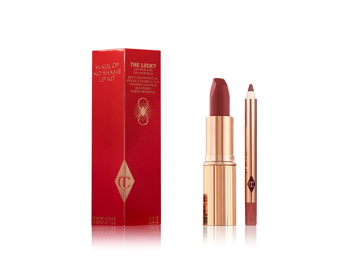 An open lipstick in a berry-rose shade with a matching lip liner pencil placed along a blood-red box they come in. 