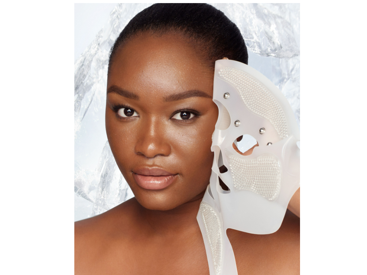 Deep-tone brunette model removing a reusable, white-coloured mask, revealing glowy, flawless, and lifted skin. 