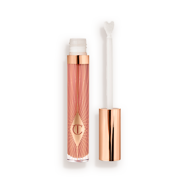 Un lucidalabbra rosa nude aperto in formato standard con applicatore a forma di cuore e tappo rosa dorato accanto. 