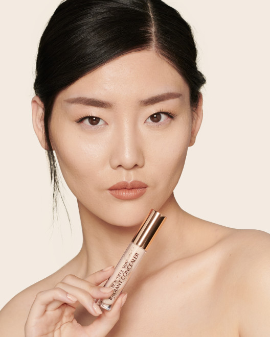 Fair-tone model with brown eyes wearing a radiant, concealer that brightens, covers blemishes, and makes her skin look fresh along with nude lip gloss and subtle eye makeup.